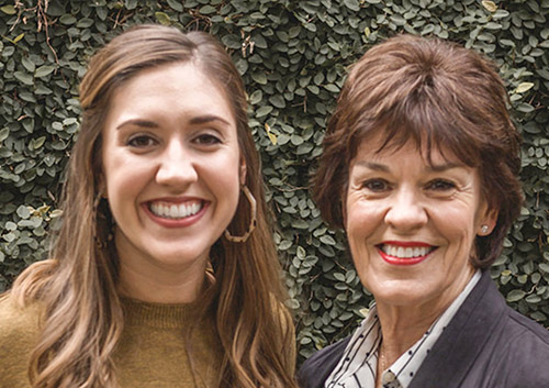 Drs. Jan T. Bagwell &amp; Jessica J. Johnston, DDS together smiling in front of a green leaf wall.